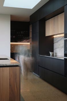 a blurry image of people in a kitchen with black cabinets and marble counter tops