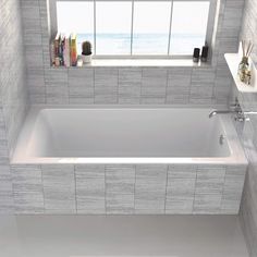 a bath tub sitting under a window next to a shelf filled with books and other items