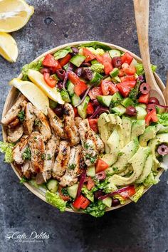 a salad with chicken, lettuce, olives, tomatoes and cucumber