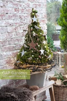 a small christmas tree sitting on top of a wooden bench next to a brick wall