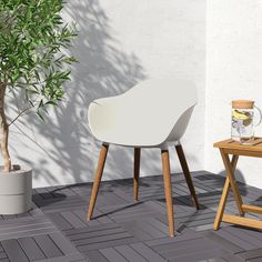 a white chair sitting on top of a wooden table next to a potted plant