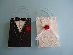 two paper bags decorated with red roses and black tuxedo are on a blue surface