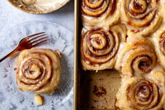 a pan filled with cinnamon rolls on top of a plate next to a bowl of cream cheese