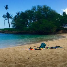 there is a blue backpack and other items on the sand at the beach by the water