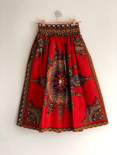 "Red Dashiki high waist full gathered skirt. Perfect for casual outfits and special occasions with pair of trainters or high heels. 100% cotton.  Elastic at the back of waist.  Two side pockets. Midi length about 76cm + 5 cm waistband. Handmade in UK.  HOW TO CHOOSE A SIZE ?   Using a measuring tape, measure the smallest part of your waist.  SIZE CHART: (CM) XS - W: 66 CM S - W: 70 CM M - W: 74 CM  L - W: 78 CM  XL - W: 82 CM  CARE INSTRUCTIONS: Hand wash only, do not bleach, hang dry, do not tumble dry, press with a cool iron on the reverse side.  Please message me before purchasing so I can check availability. If you wish this skirt in any other fabric, shorter or longer \"send message to seller\" and we can try to make something especially for you. *Depends on computer/monitor settings Red Cotton Flared Skirt Bottoms, Red Cotton Long Skirt, Red Cotton Flared Skirt, Red Flared Cotton Skirt, Red Gathered Skirt Bottoms For Summer, Red Midi Skirt With Elastic Waistband, Red Full Skirt With Elastic Waistband, Red Cotton Midi Skirt, Bohemian Red Full Skirt