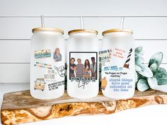 three personalized tumblers with pictures on them sitting on a piece of driftwood