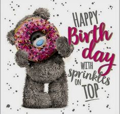 a teddy bear holding a donut with sprinkles on it