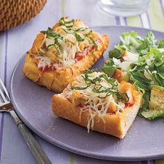 two slices of pizza on a plate next to a salad