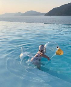 a person floating on top of a body of water with a duck shaped floater