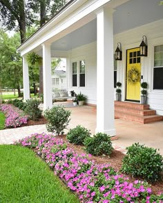 the front porch is decorated with purple flowers and greenery, along with yellow door