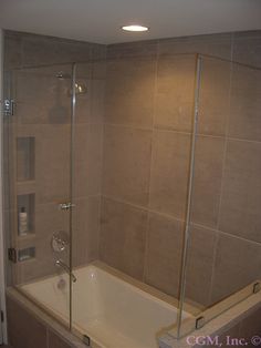 a bath tub sitting next to a shower with glass doors on the wall and floor