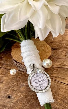 a white flower with a tag attached to it on top of a piece of wood