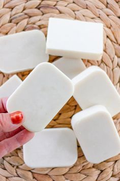 a hand holding some white soap on top of a woven basket