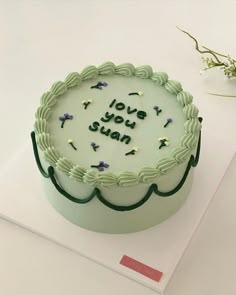 a green cake with the words i love you susan on it sitting on top of a table