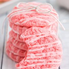 pink cookies with white icing stacked on top of each other