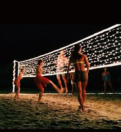 people are playing volleyball on the beach at night