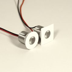 two metal objects with wires attached to them on a white surface, one is plugged into the other