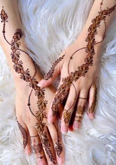 two hands with henna tattoos on them