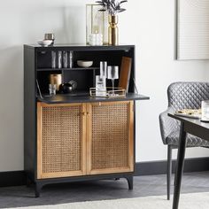 a black and brown cabinet sitting next to a dining room table with plates on it