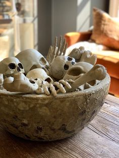 a bowl filled with skulls and bones on top of a wooden table