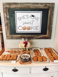 a table topped with lots of food next to a framed sign that says she's one smart cookie