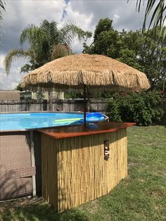 an umbrella over a bar in the backyard next to a swimming pool with a tiki hut