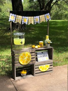 a lemonade stand is set up outside in the grass with some lemons on it