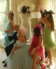 a group of women dressed in costumes posing for the camera with one woman sitting on a chair