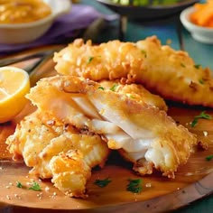 some food on a wooden plate with lemons and other foods in bowls behind it