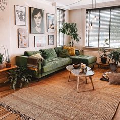 a living room with green couches and pictures on the wall above them, along with potted plants