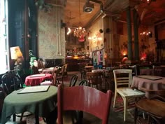 an empty restaurant with tables and chairs covered in tablecloths, lights hanging from the ceiling