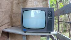 an old television set sitting on top of a wooden table next to a stone wall