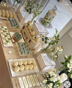 an assortment of desserts and pastries displayed on a table with flowers in vases