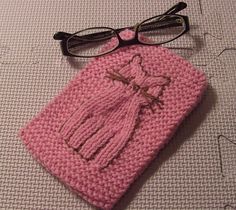 a pink crocheted bag with a tassel and glasses on top of it