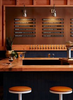 a bar with three stools in front of it and several menus on the wall