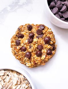 an oatmeal cookie with chocolate chips next to it on a white surface