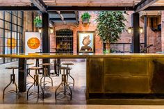 an industrial style bar with stools and tables in the center, surrounded by brick walls