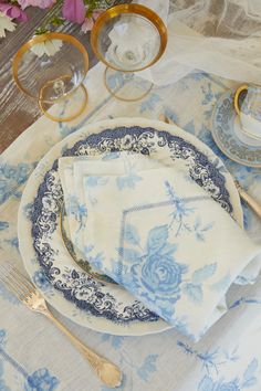 a blue and white place setting with flowers in the background