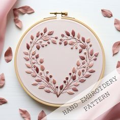 a heart shaped embroidery pattern with pink leaves on it and the words hand embroidery written in white