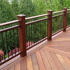 a wooden deck with metal railings and trees in the background