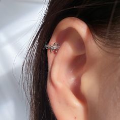 a woman's ear is shown with two small piercings