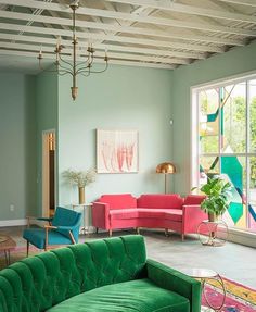 a living room with green couches and pink chairs