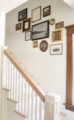 there are many framed pictures on the wall next to the bannister and stairs