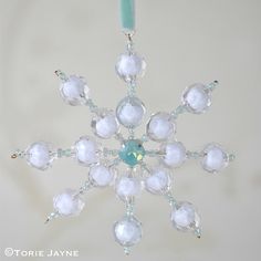 a glass snowflake ornament hanging from a blue string with white beads