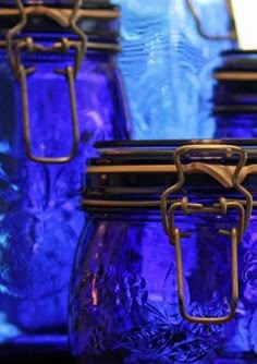 blue glass jars are lined up on the shelf in front of each other with metal handles