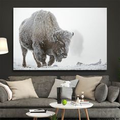 a living room with a couch, coffee table and large bison painting on the wall