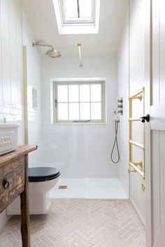 a bathroom with a toilet, sink and window in the ceiling is white tile flooring