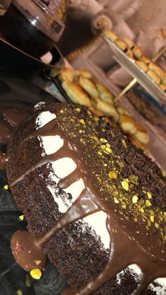 there is a chocolate cake with white frosting on the top and other pastries in the background