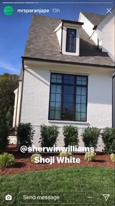 a white house with black windows and bushes in the front yard is featured on an instagram page