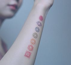 a woman with a tattoo on her arm that has five different colors and shapes in it